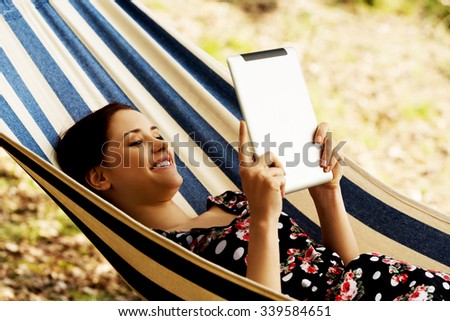 Woman Relaxing In Hammock With  Tablet computer