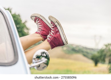 Woman Relaxing In Her Car While Driving In The Countryside - Young  Cool Girl With Shoes Out Of The Automobile Window To Enjoy The View