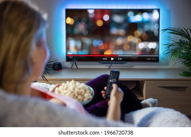Woman relaxing at home in evening and watching TV