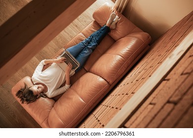 Woman Relaxing At Home On The Sofa Working Typing On Laptop Computer. Top View Shot