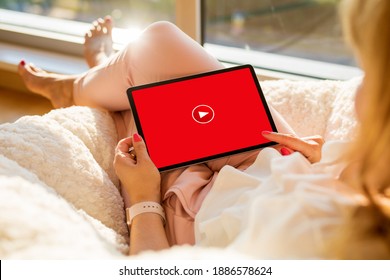 Woman relaxing at home and watching videos online on tablet