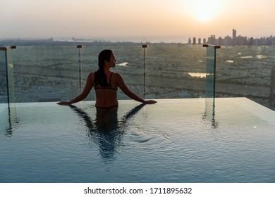 Woman Relaxing In Infinity Pool With Sunset City View. Relaxing Vacation.  Dubai UAE