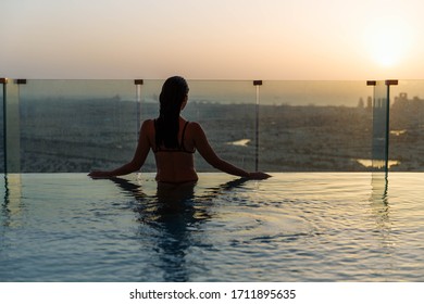 Woman Relaxing In Infinity Pool With Sunset City View. Relaxing Vacation.  Dubai UAE