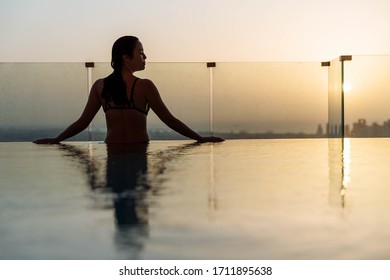 Woman Relaxing In Infinity Pool With Sunset City View. Relaxing Vacation.  Dubai UAE