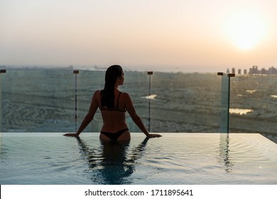 Woman Relaxing In Infinity Pool With Sunset City View. Relaxing Vacation.  Dubai UAE