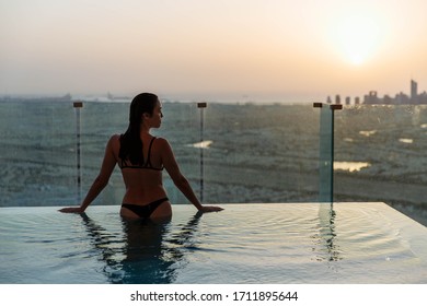 Woman Relaxing In Infinity Pool With Sunset City View. Relaxing Vacation.  Dubai UAE