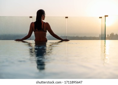 Woman Relaxing In Infinity Pool With Sunset City View. Relaxing Vacation.  Dubai UAE