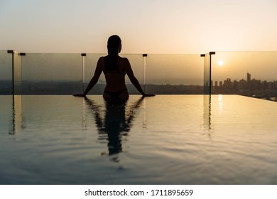 Woman Relaxing In Infinity Pool With Sunset City View. Relaxing Vacation.  Dubai UAE