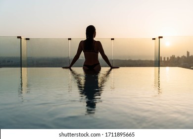 Woman Relaxing In Infinity Pool With Sunset City View. Relaxing Vacation.  Dubai UAE