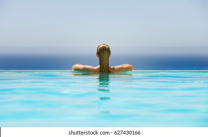 Woman Relaxing In Infinity Swimming Pool 