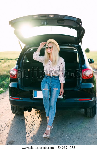 Woman relaxing\
inside car trunk and watching on sea. Fall trip in sunset. Freedom\
travel concept. Autumn\
weekend.