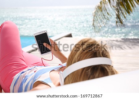 Woman relaxing in long chair with headphones on
