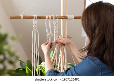 Woman relaxing and making macrame at home with different knots. Stay at home hobbies.