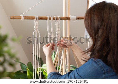 Woman relaxing and making macrame at home with different knots. Stay at home hobbies.