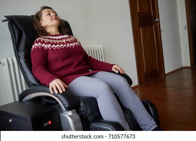 Woman relaxing in massage armchair.