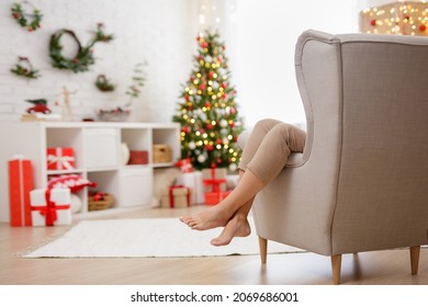 Woman relaxing on armchair in decorated room with christmas tree