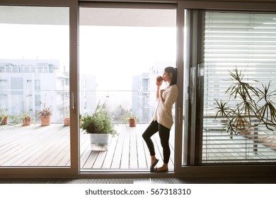Woman relaxing on balcony holding cup of coffee or tea