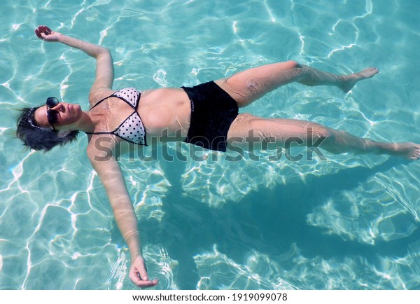 Woman relaxing\
on beach floating in the\
water.