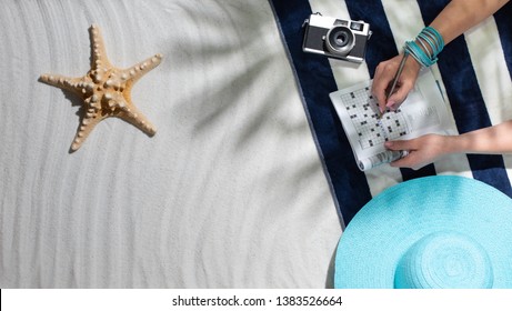 Woman relaxing on the beach and solving crosswords, summertime and vacations concept, blank copy space - Powered by Shutterstock