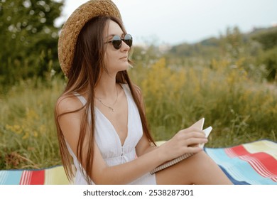 A woman is relaxing on a colorful blanket in a sunny field, reading a book - Powered by Shutterstock