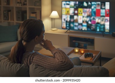 Woman relaxing on the couch and choosing a movie on her television