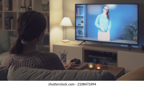 Woman Relaxing On The Couch And Watching An Unboxing Video Online On Her Smart TV