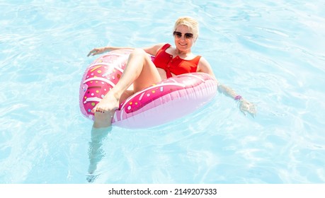 Woman relaxing on donut lilo in the pool at private villa. Inflatable ring and mattress. Summer holiday idyllic. High view from above