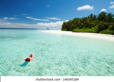 Woman relaxing on inflatable mattress in the sea. Happy island lifestyle. Vacation at Paradise. Happy woman enjoy crystal-blue sea of tropical beach. Ocean beach relax, travel to Maldives islands