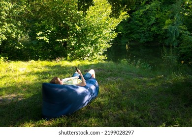 Woman Relaxing On Inflatable Sofa Out In The Wild Camping.
Air Sofa Or Lamzac On The Nature.