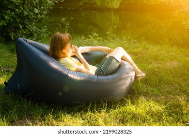 Woman Relaxing On Inflatable Sofa Out In The Wild Camping.
Air Sofa Or Lamzac On The Nature.