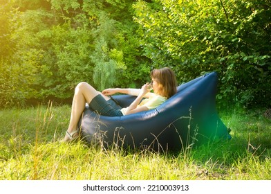 Woman Relaxing On Inflatable Sofa Out In The Wild Camping.
Air Sofa Or Lamzac On The Nature.