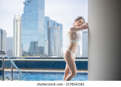 Woman Relaxing On A Rooftop Pool With Beautiful City View Background.