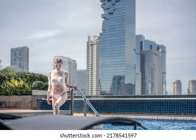 Woman Relaxing On A Rooftop Pool With Beautiful City View Background.