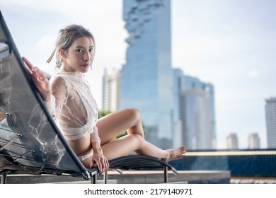 Woman Relaxing On A Rooftop Pool With Beautiful City View Background.