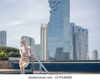 Woman Relaxing On A Rooftop Pool With Beautiful City View Background.