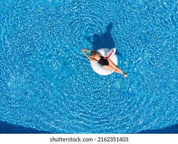 Woman Relaxing In Pool Float Unicorn Inflatable Ring Floating On Turquoise Pool Water. Aerial Top View From Drone