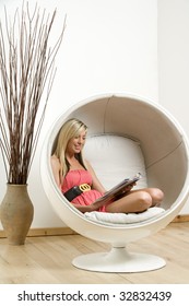 Woman relaxing and reading in an egg chair