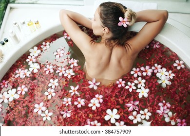 Woman Relaxing In Round Outdoor Bath With Tropical Flowers, Organic Skin Care, Luxury Spa Hotel, Lifestyle Photo, Top View