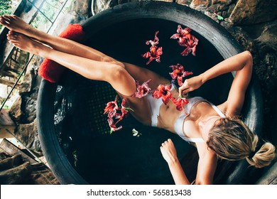 Woman relaxing in round outdoor bath with tropical flowers. Organic skin care in kawa hot bath in luxury spa resort. - Powered by Shutterstock