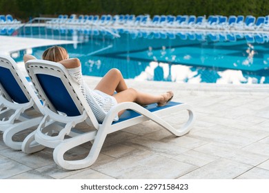 Woman relaxing sitting on sunbed by pool  - Powered by Shutterstock