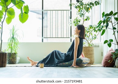 A woman relaxing surrounded by foliage plants in the room - Shutterstock ID 2157193481