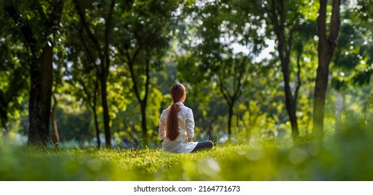 Woman relaxingly practicing meditation in the forest to attain happiness from inner peace wisdom with beam of sun light for healthy mind and soul - Shutterstock ID 2164771673