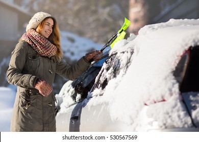 Woman Remove Snow From Car With Snow Brush.