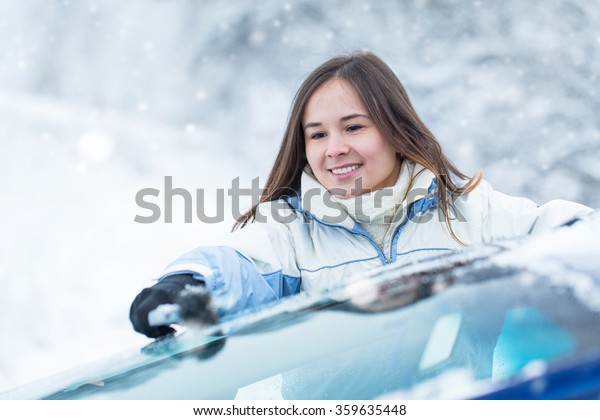 Woman remove
snow from windshield with snow
brush.