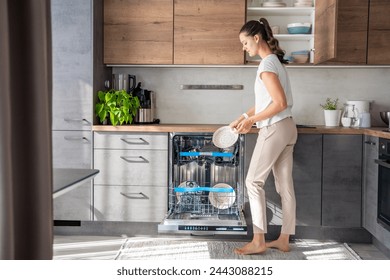 A woman removes clean ceramic dishes from the dishwasher. Household and useful technology concept. High quality photo. 