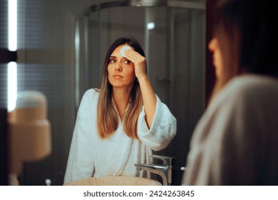 
					Woman Removes Make-up with a Cotton Pad in the Mirror. Pretty millennial girl using tonic products in her skin care
					