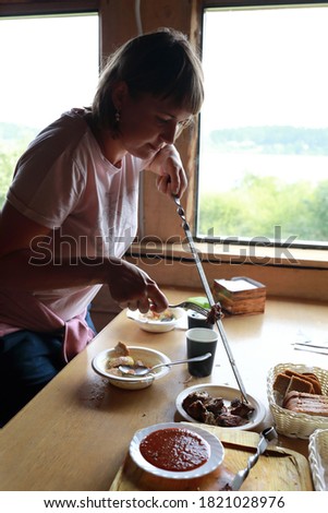 Woman removes meat from skewer in restaurant