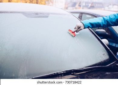 Woman Removing Ice From Car Windshield With Glass Scraper. Frosty Morning