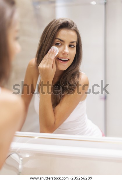 Woman removing makeup from\
her face