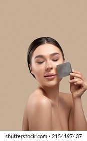 Woman removing oil from face using blotting papers. Closeup Portrait Of Beautiful Healthy Girl With Nude Makeup. Perfect Soft Skin With Oil Absorbing Tissue Sheets.
